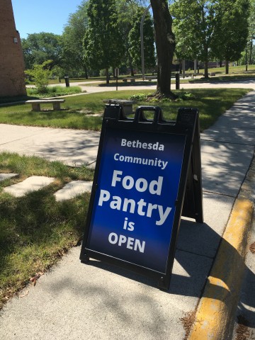 a sandwich board with the words "Bethesda Community Food Bank is open" on it