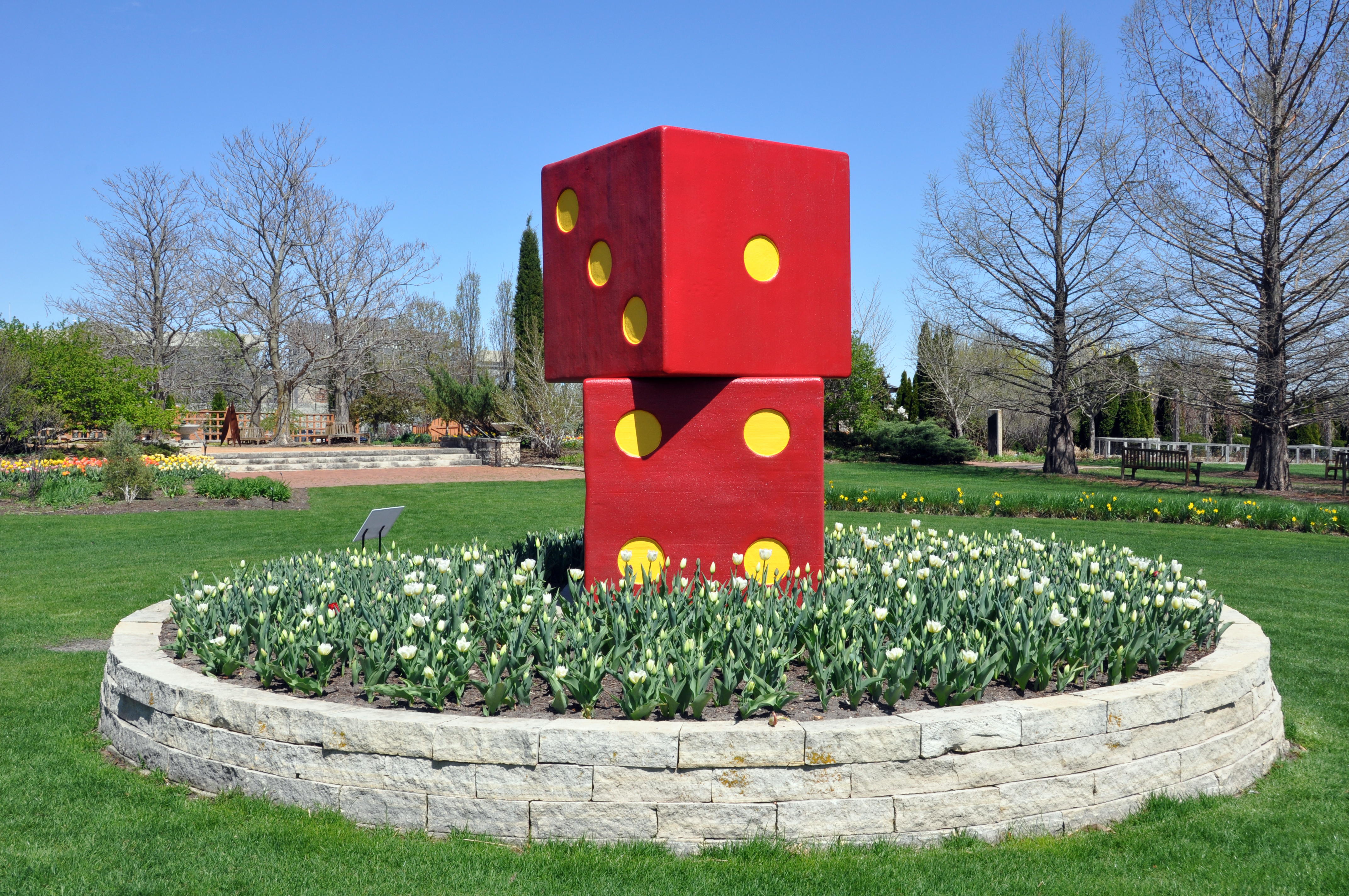 Two large dice sculptures are nestled in a flower bed.