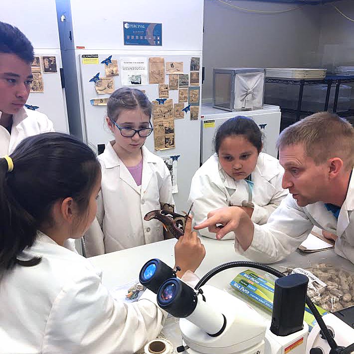 Children and adult in lab coats with insects