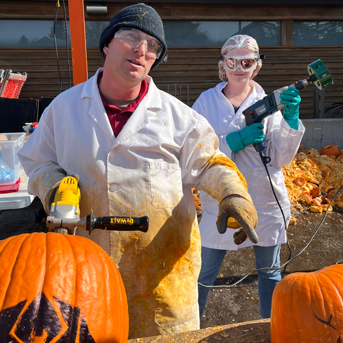 Nathan and Kim gutting pumpkins with power tools.