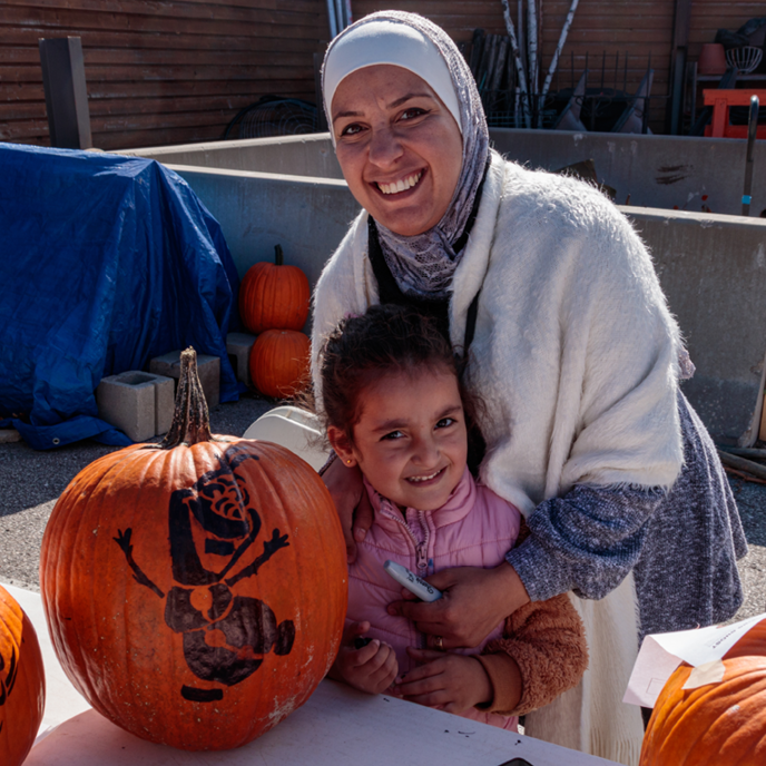 A mother and daughter smile together with a newly-traced pumpkin.