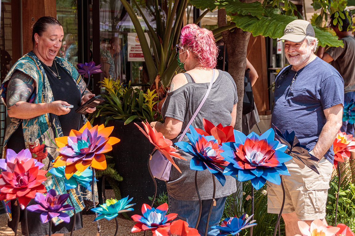 People purchasing colorful metal garden sculptures of flowers.