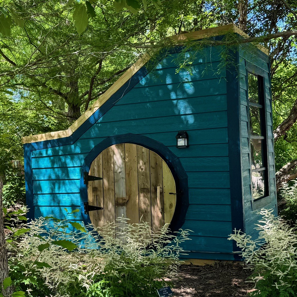 Blue playhouse in the woods with round door