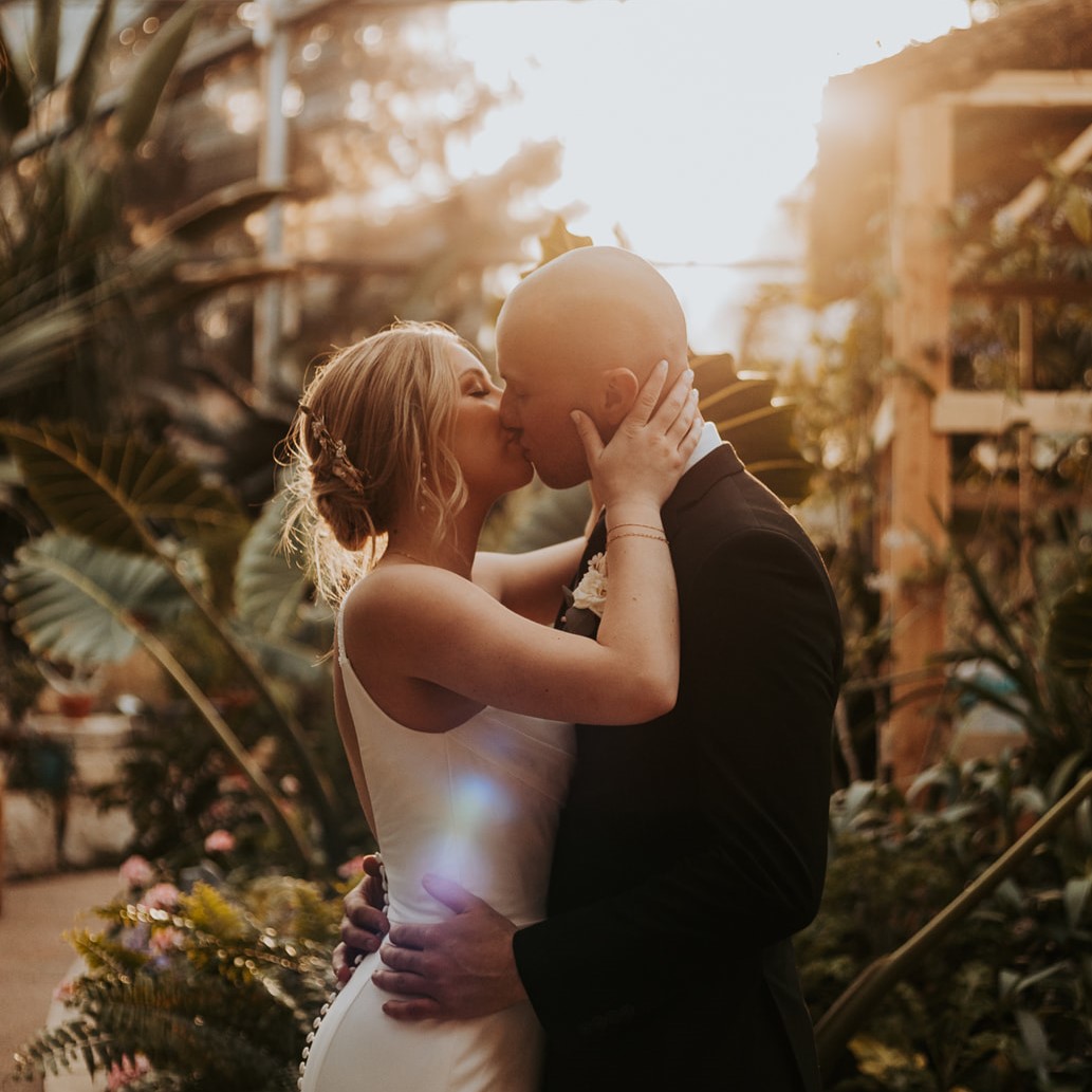 Bride and groom kissing in a garden