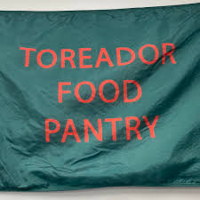 Green flag with red letters which reads "Toreador Food Pantry"