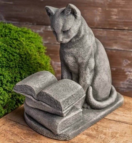 a concrete statue of a cat reading a book