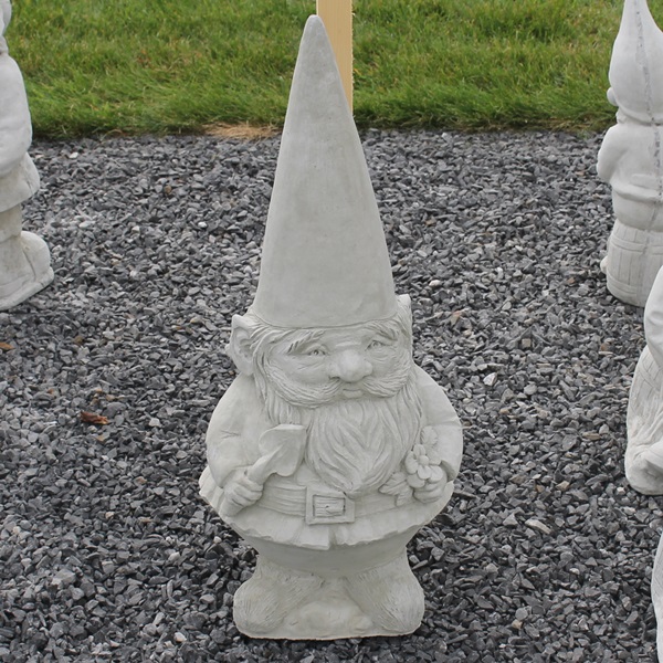 a small concrete unpainted gnome with a trowel and flowers