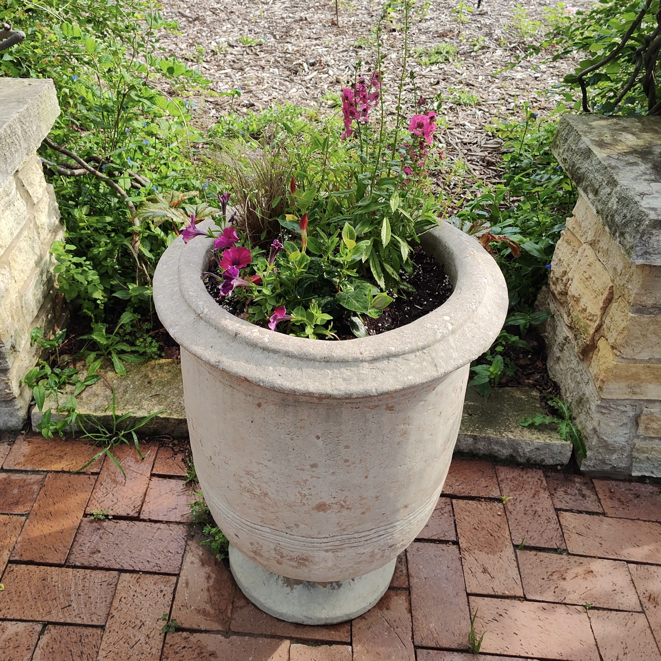 tall, skinny, stone containers with colorful flowers
