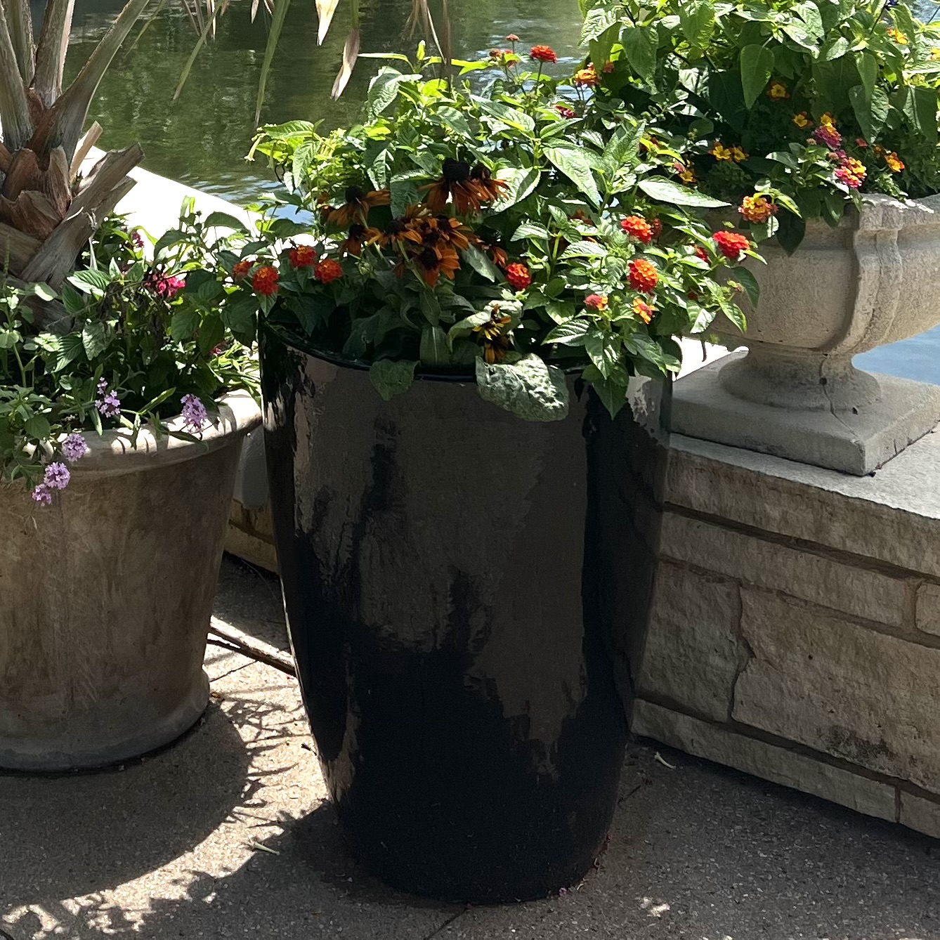 A tall, black container with colorful flowers inside
