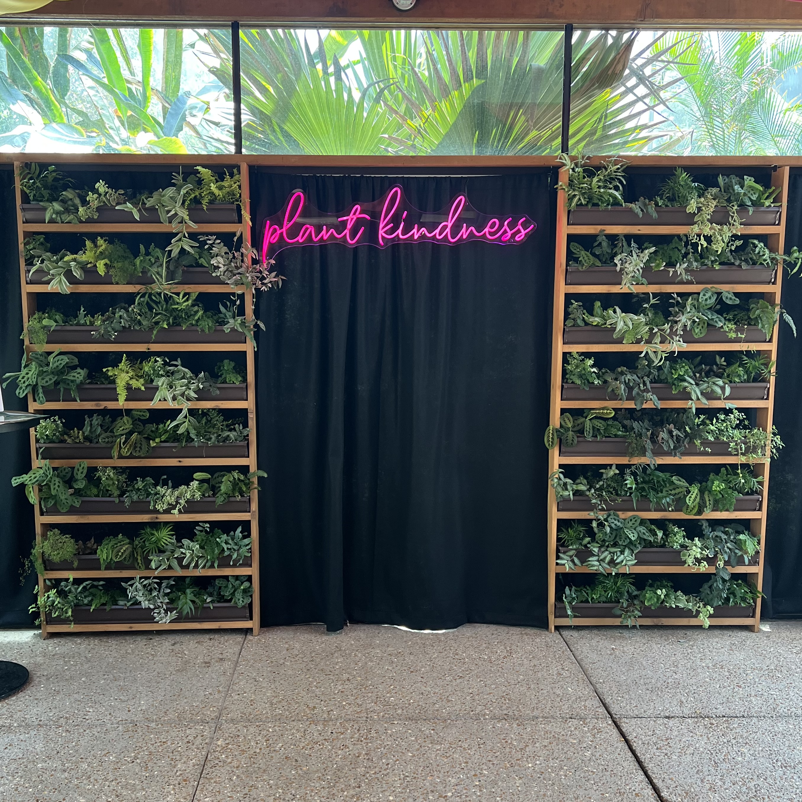 A living plant wall near the conservatory with a neon sign in the middle
