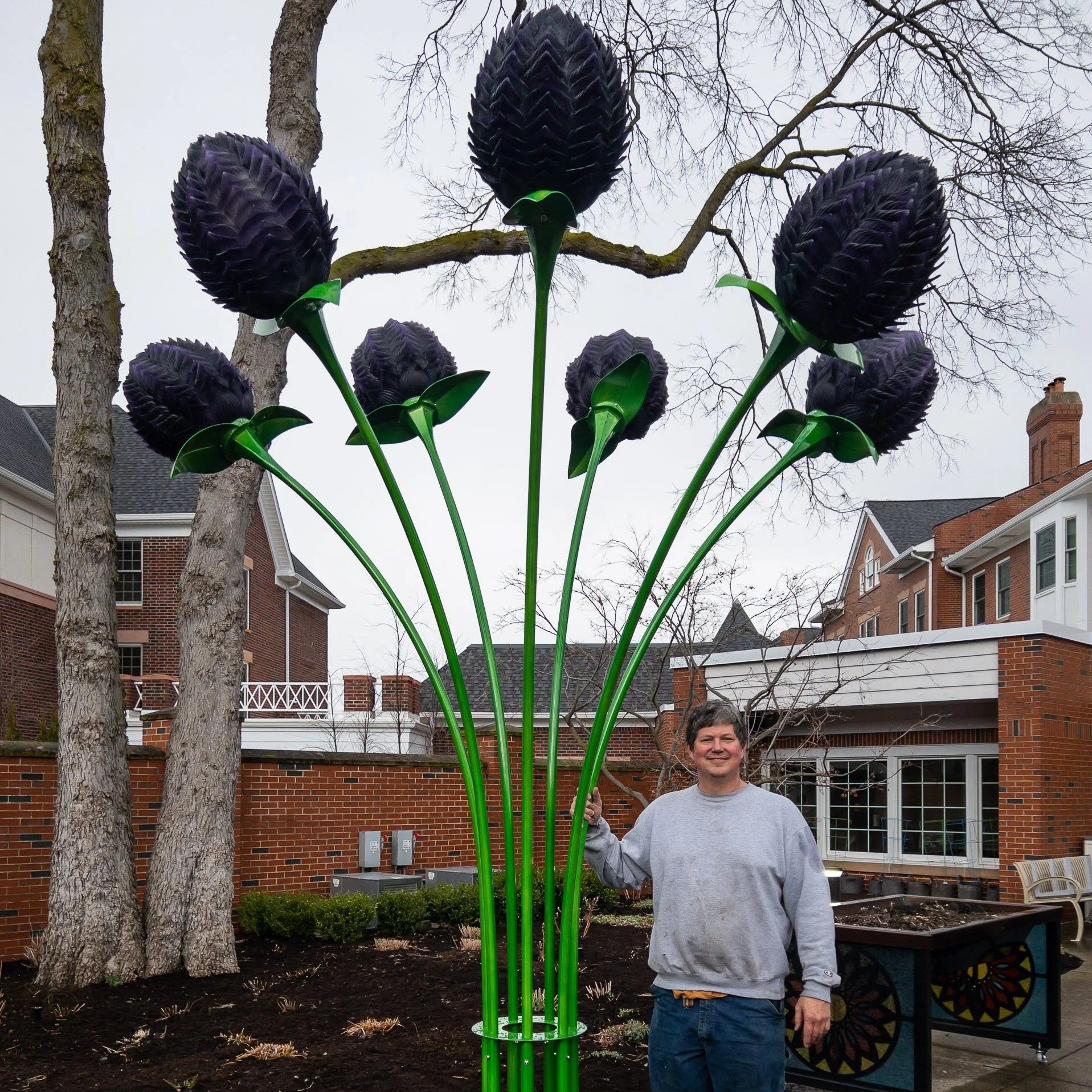Artist standing next gigantic flower sculpture