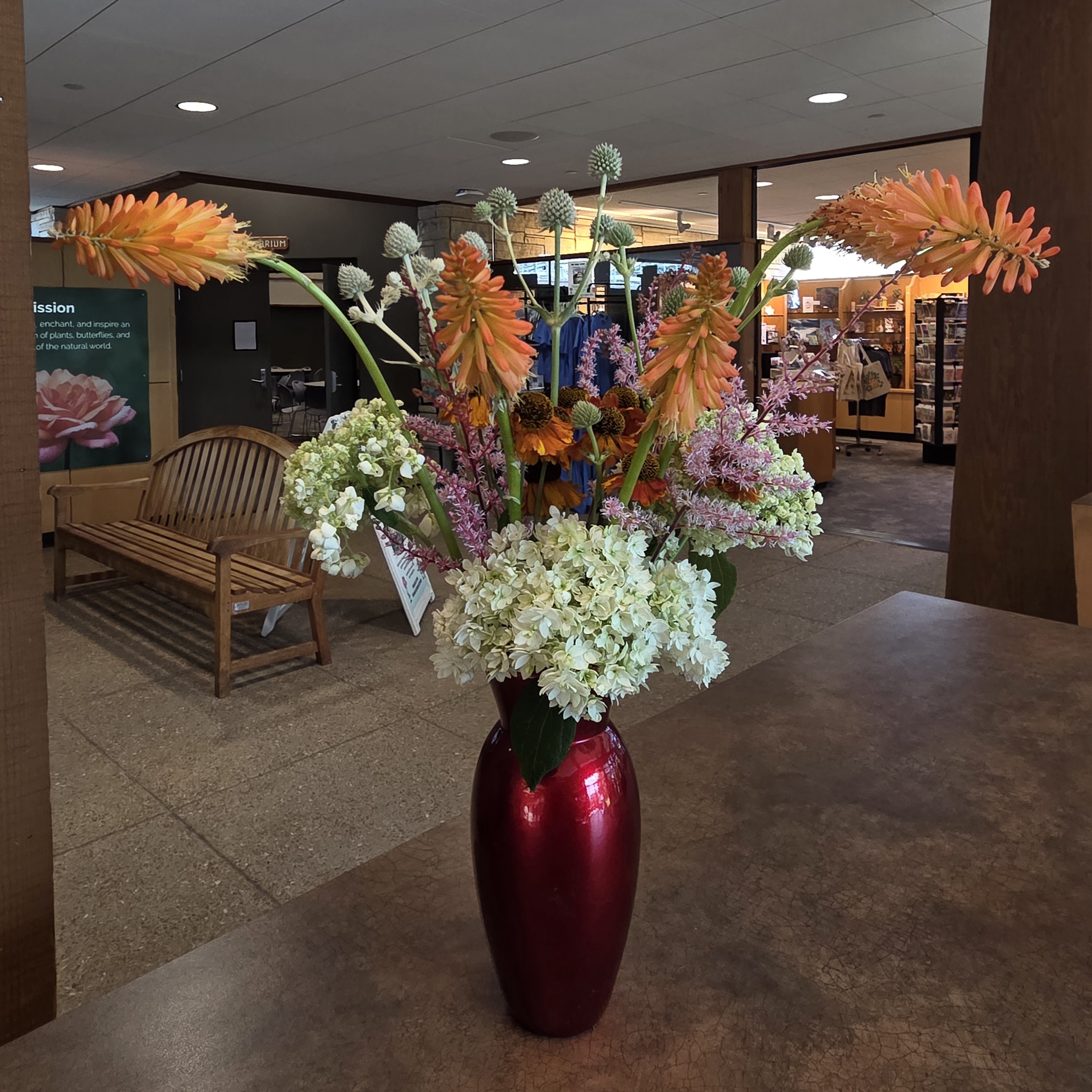 A red vase with white, orange, and pink flowers.