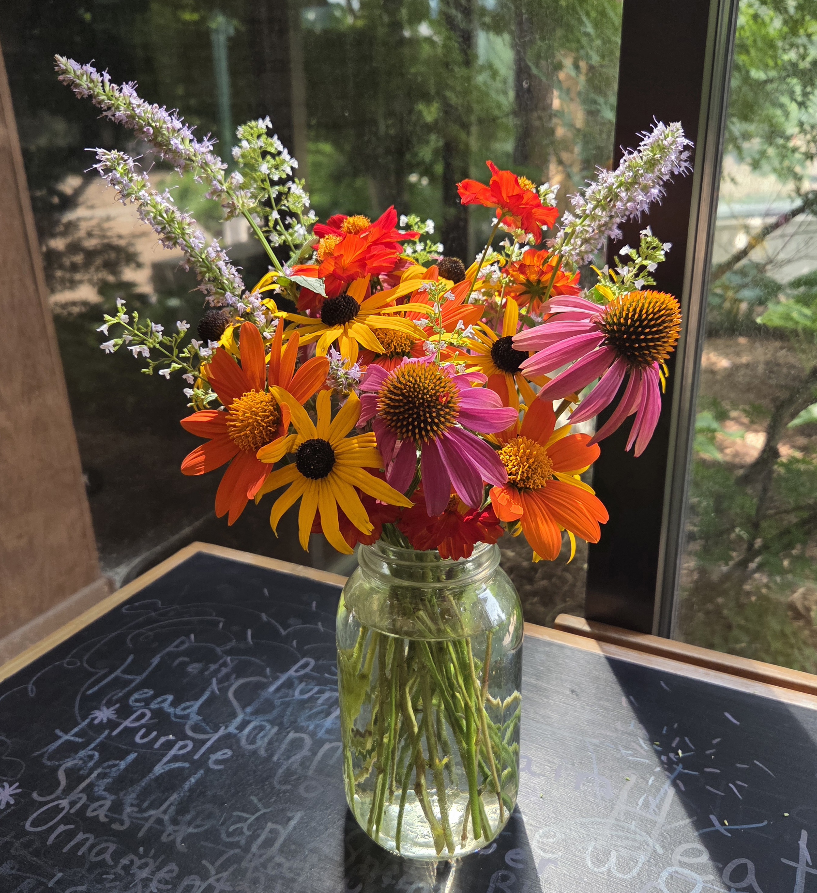 A Mason jar with an assortment of white, orange, and purple flowers