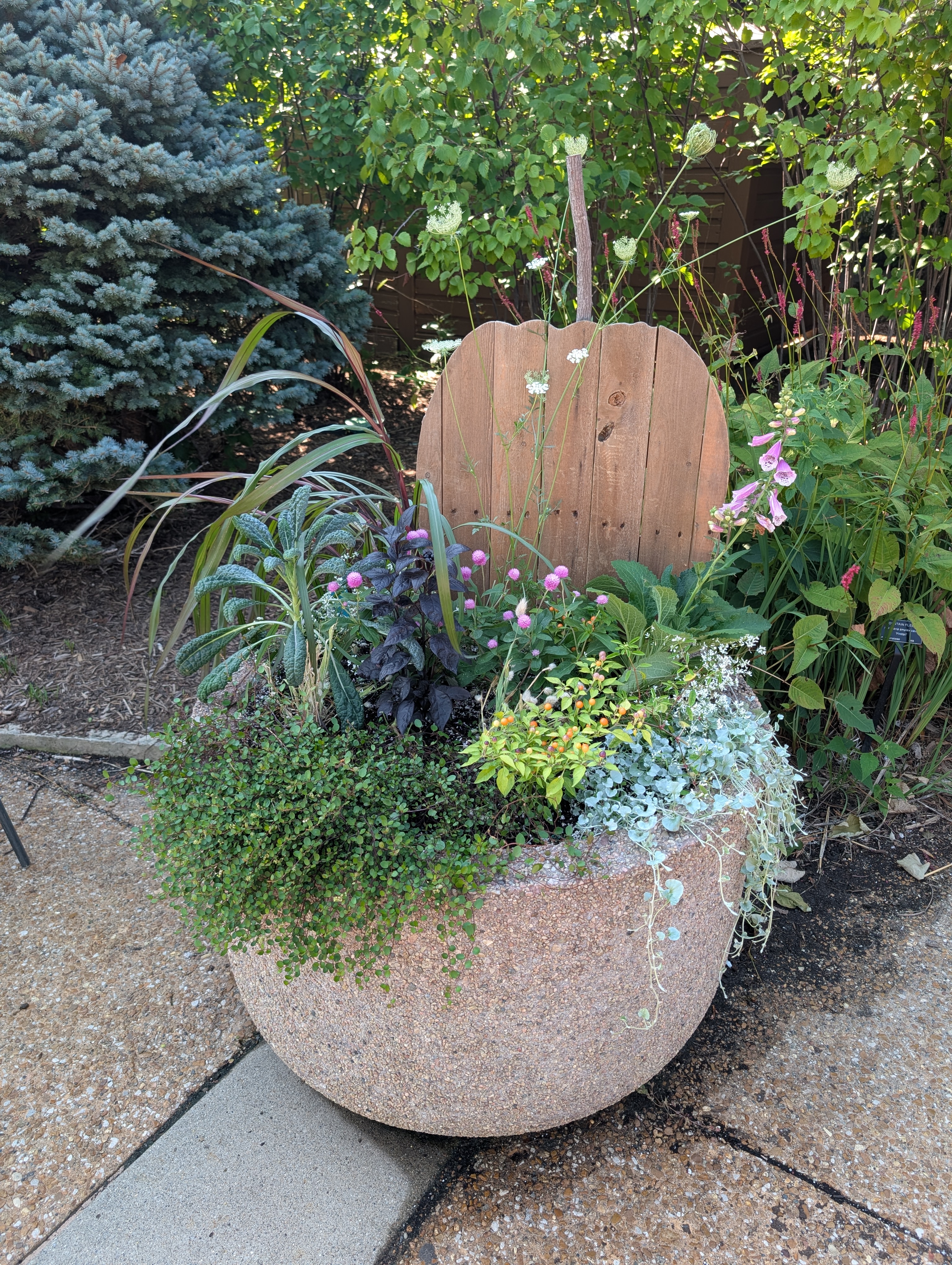 Concrete container with wooden pumpkin cut out and fall plants