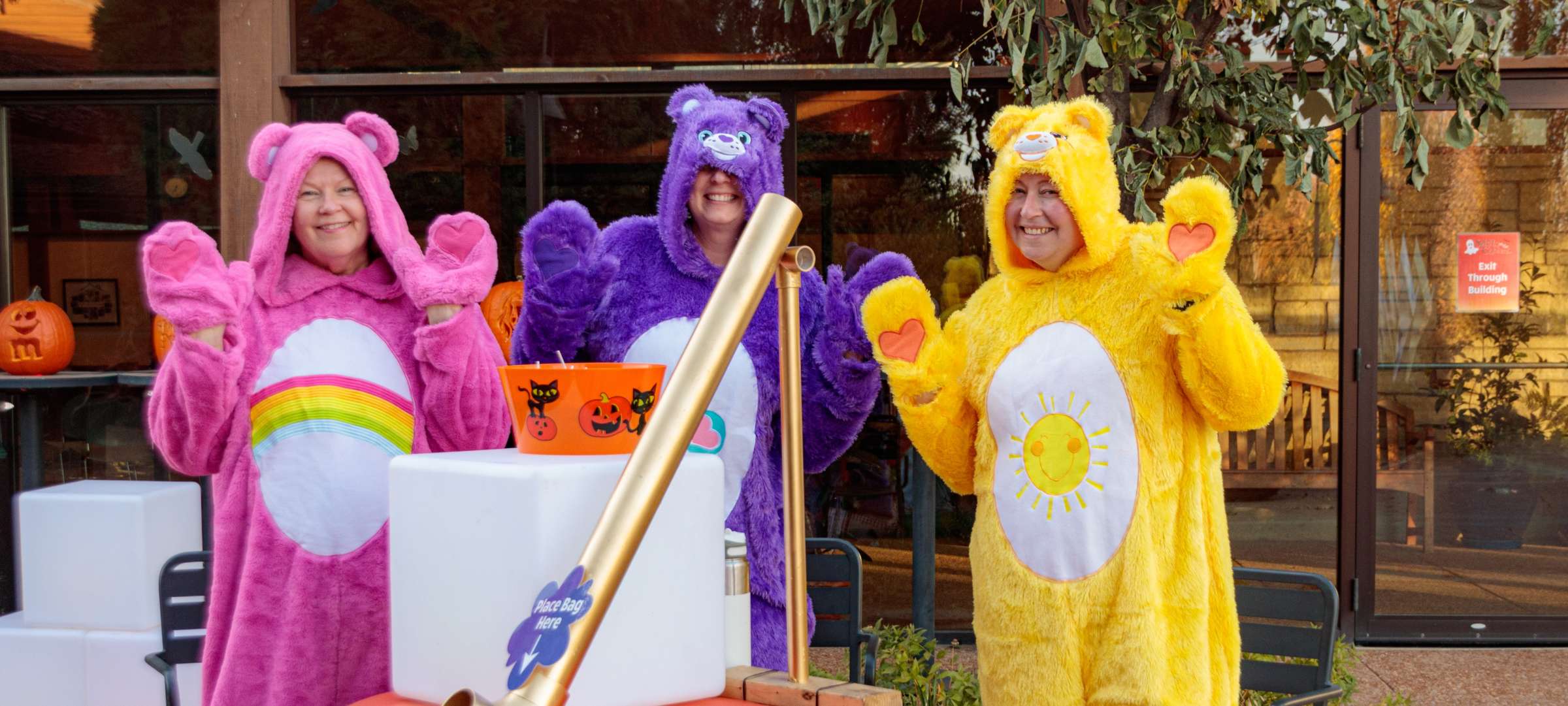Three volunteers dressed a Care Bears stand behind a candy chute at Spirits in the Gardens.
