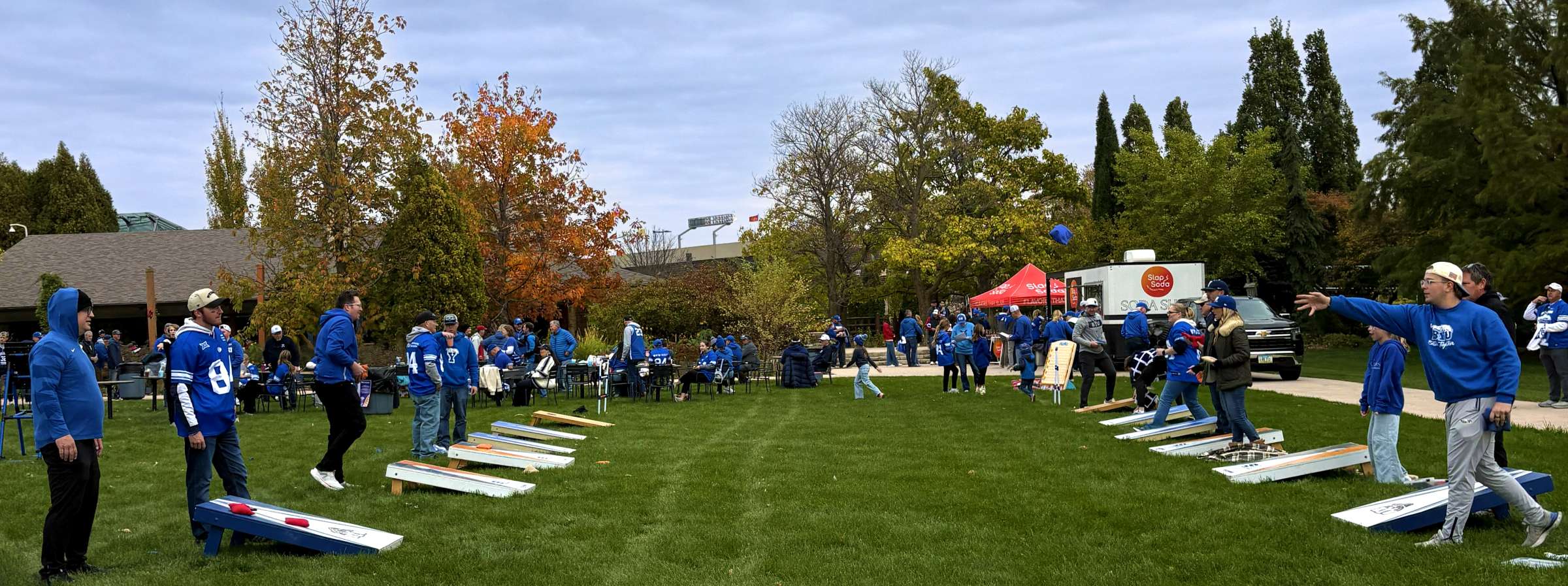 Football fans playing bags games on a lawn duing a tailgate