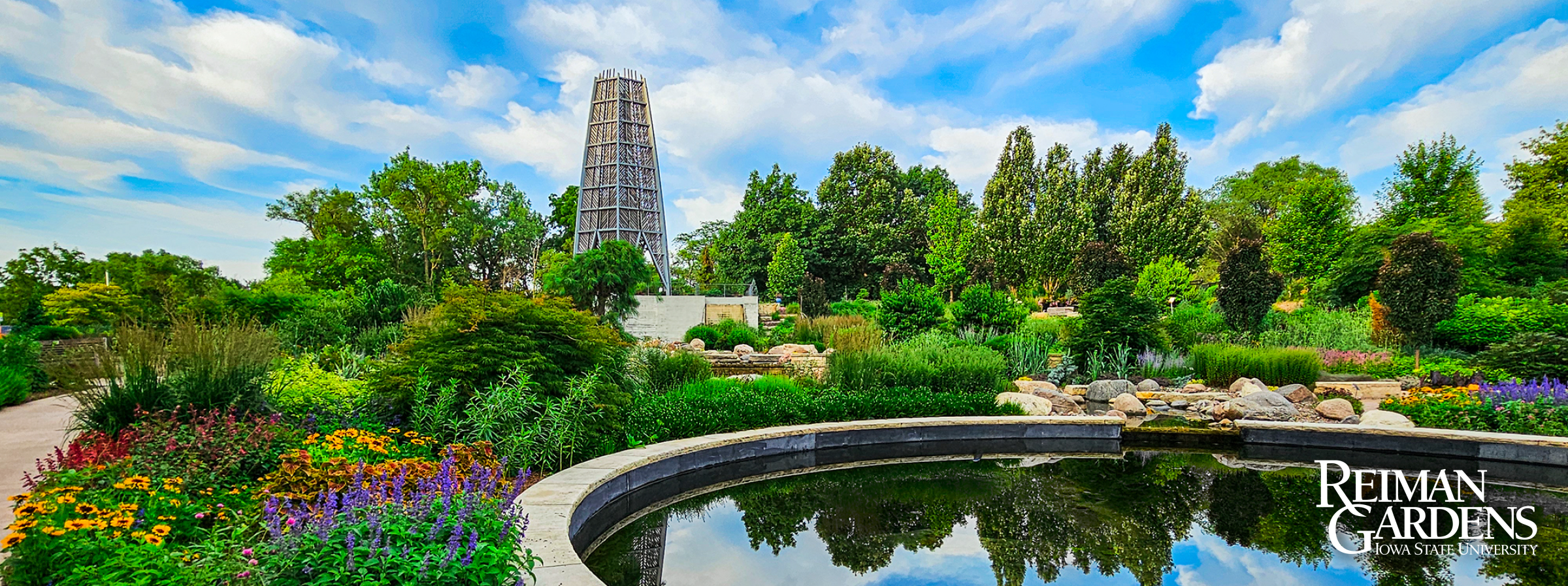 Wide view of public garden with a reflecting pool and tower