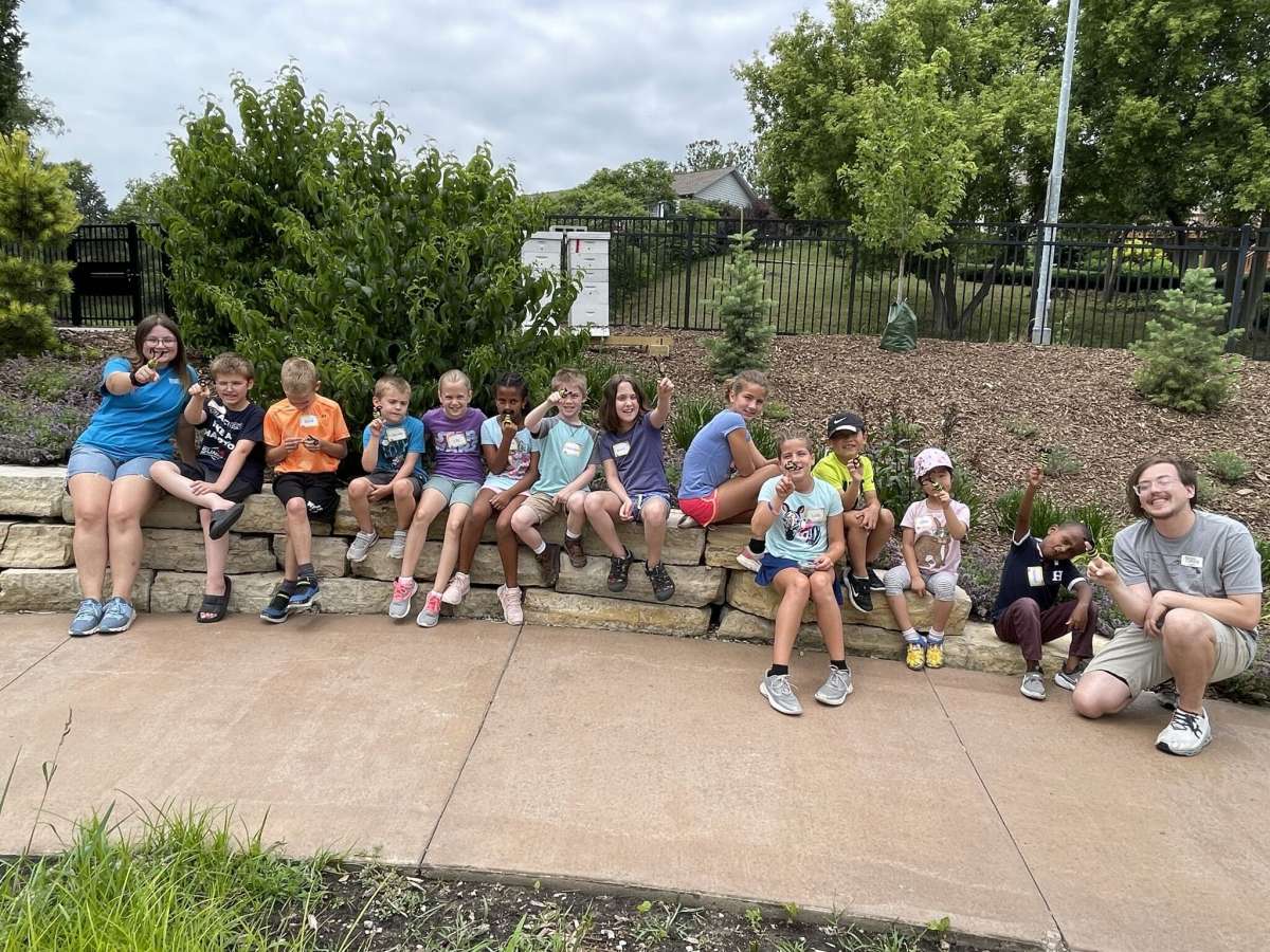 Staff  and youth day camp participants stop to pose for a picture with their pollinator-themed finger puppets.