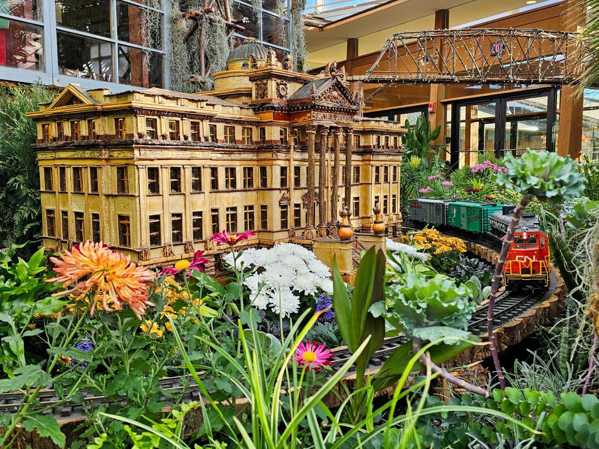 Garden-scale train and miniature building in a garden conservatory