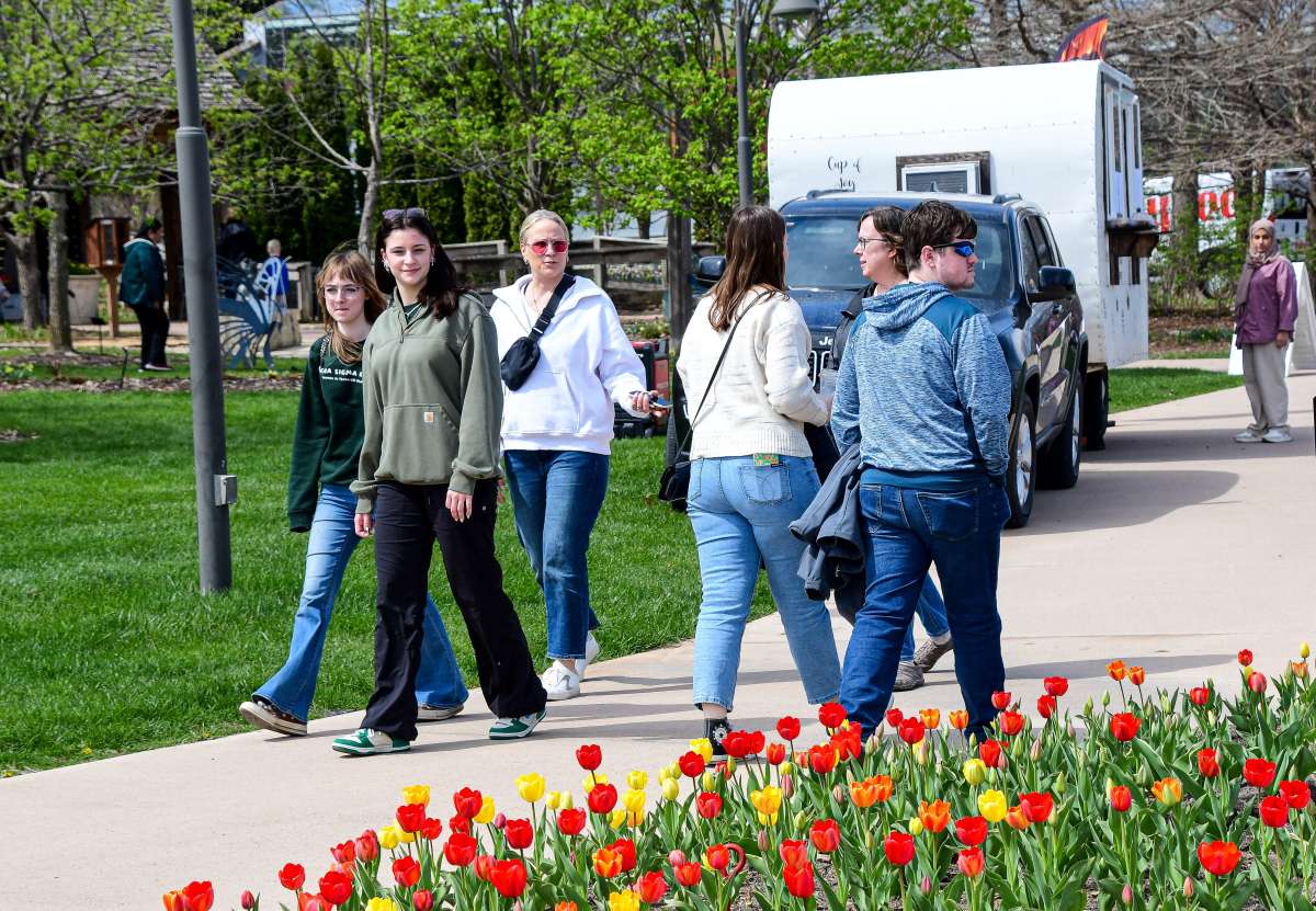 Adults walking past tulips and food trucks