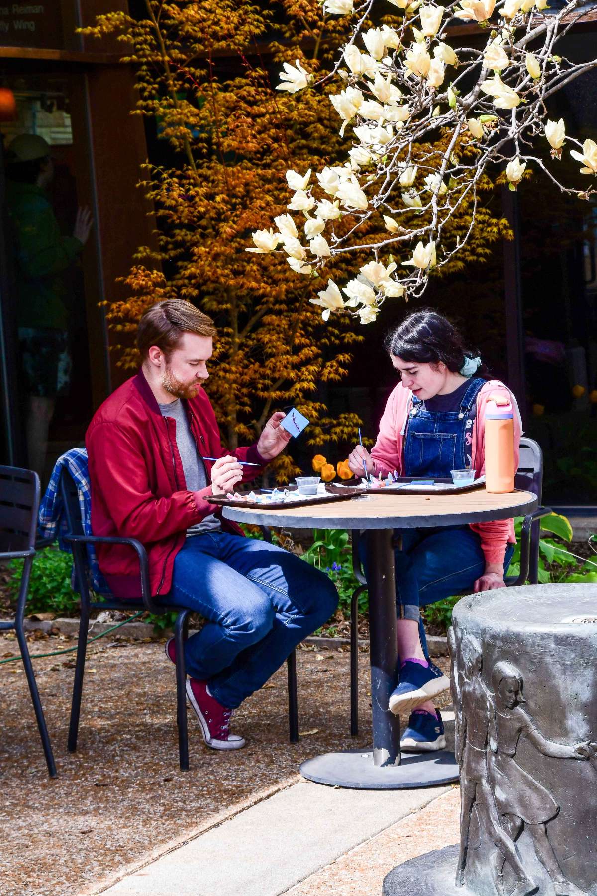 Young adults painting mini canvases at an outdoor table