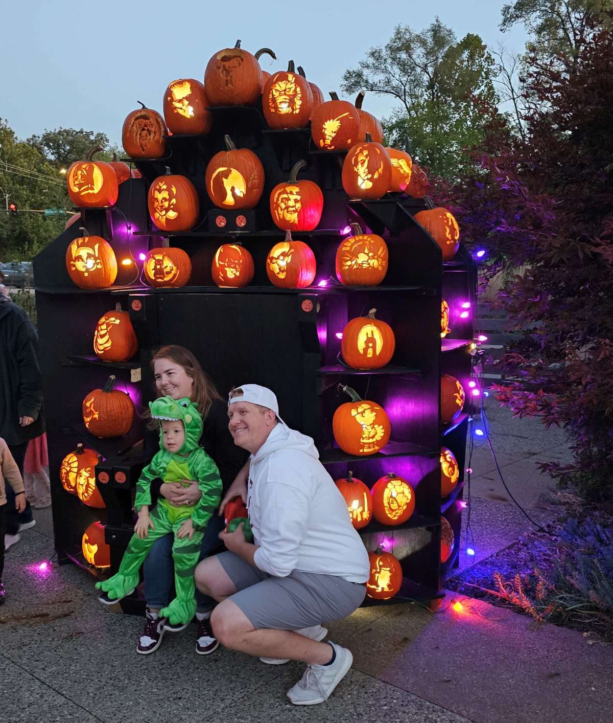 A family posing in costume in front of a throne of pumpkins