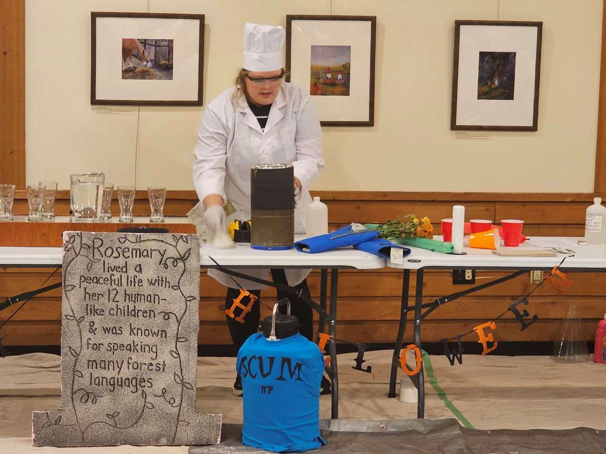 A college student dressed in a lab coat performs chemistry experiments