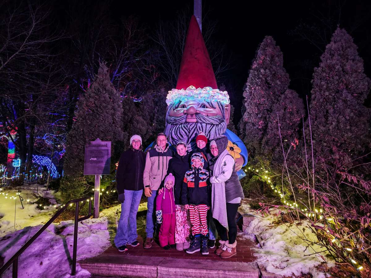 Family poses in front of a giant gnome statue at night.