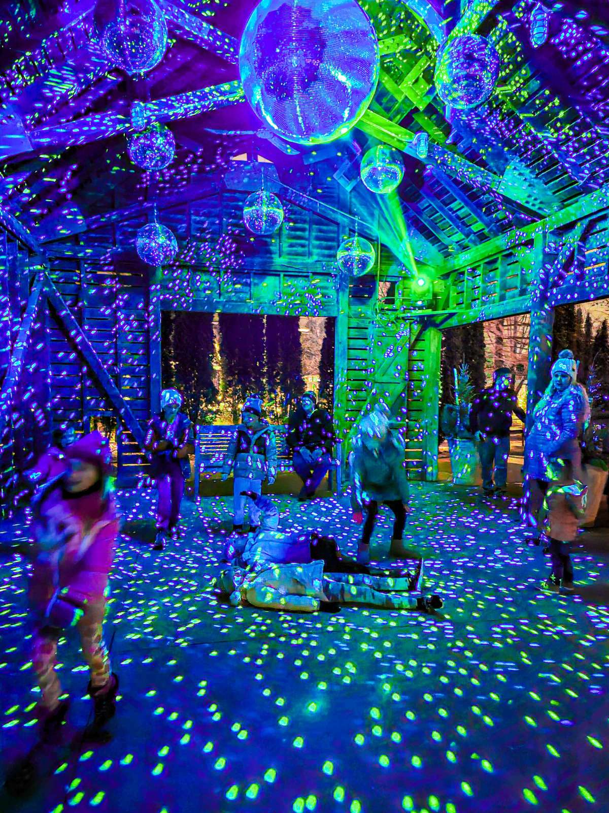 Children playing in a room full of twirling disco balls with laser lights reflecting all around.