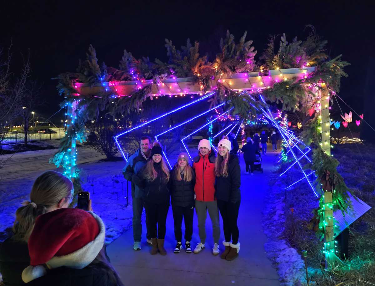 Family posing in front of a colorful lighted tunnel at a light show
