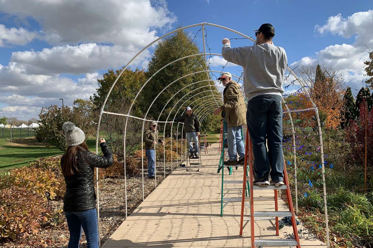 Volunteers install a lighted tunnel at Reiman Gardens