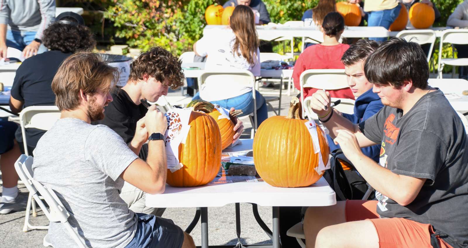 a group of ISU students work together tracing designs onto pumpkins