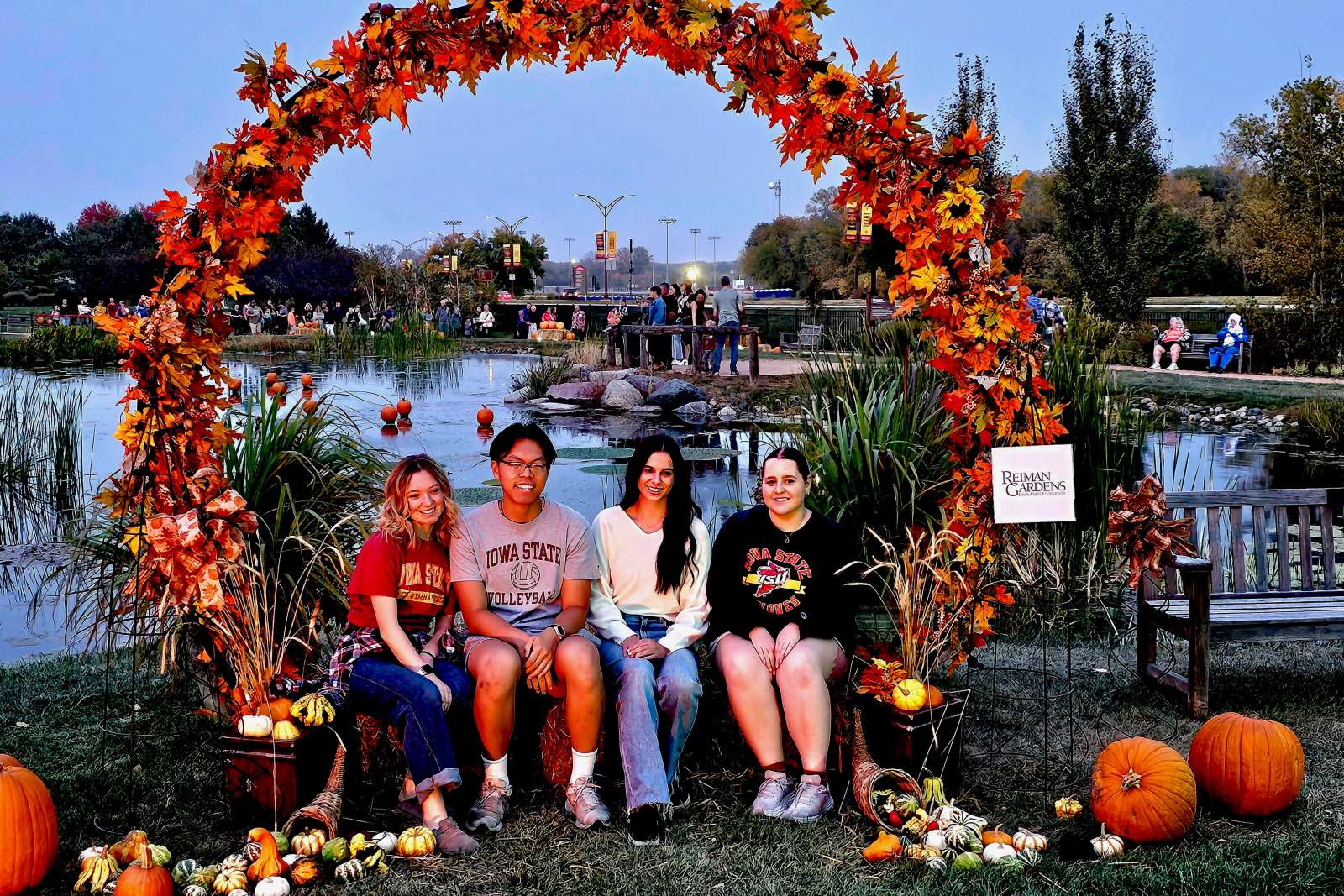 People posing for photos under an arch of fall leaves