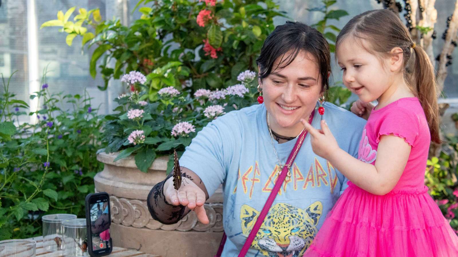 Woman and little girl looking at butterflies in a garden