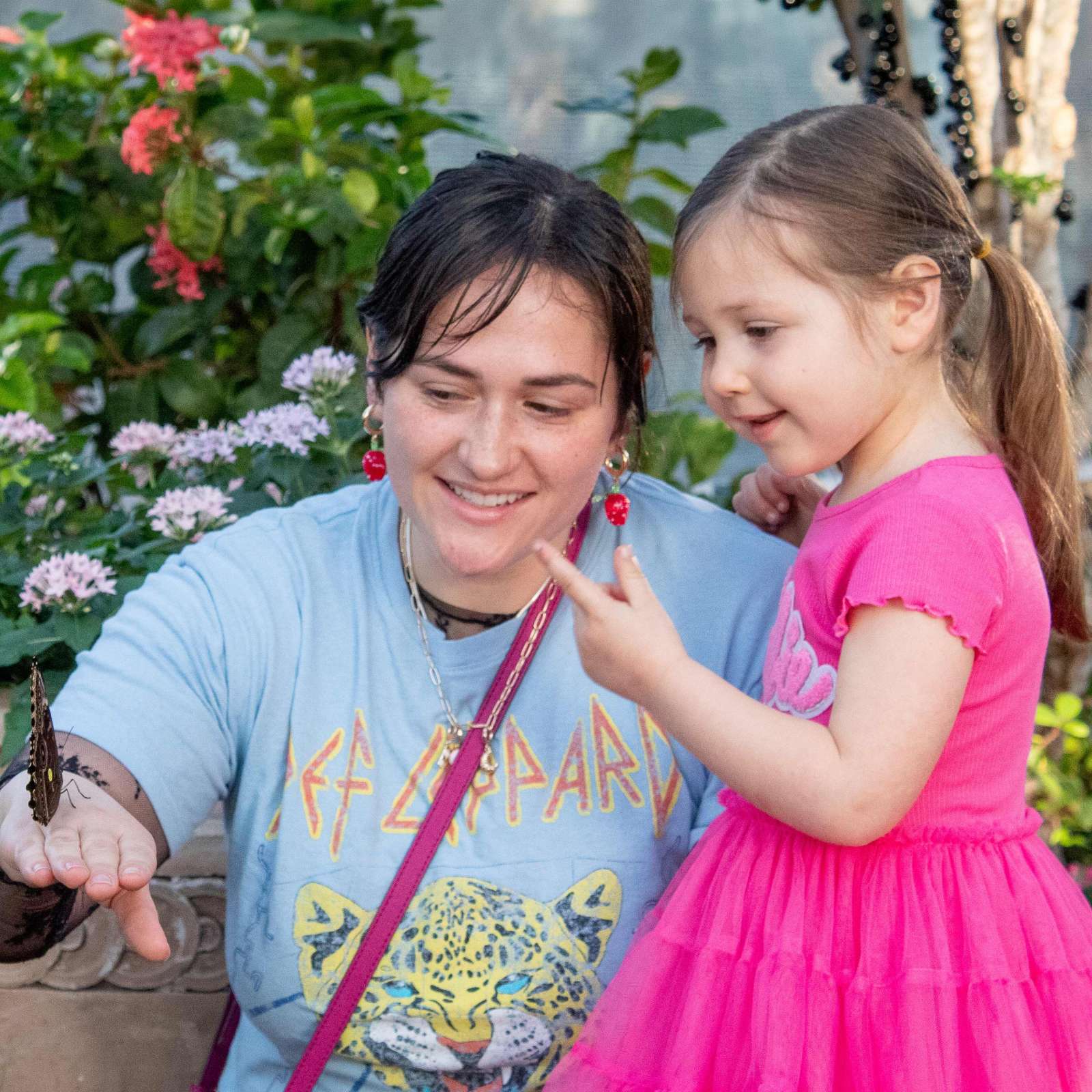 Woman and young girl looking at a butterfly in a garden