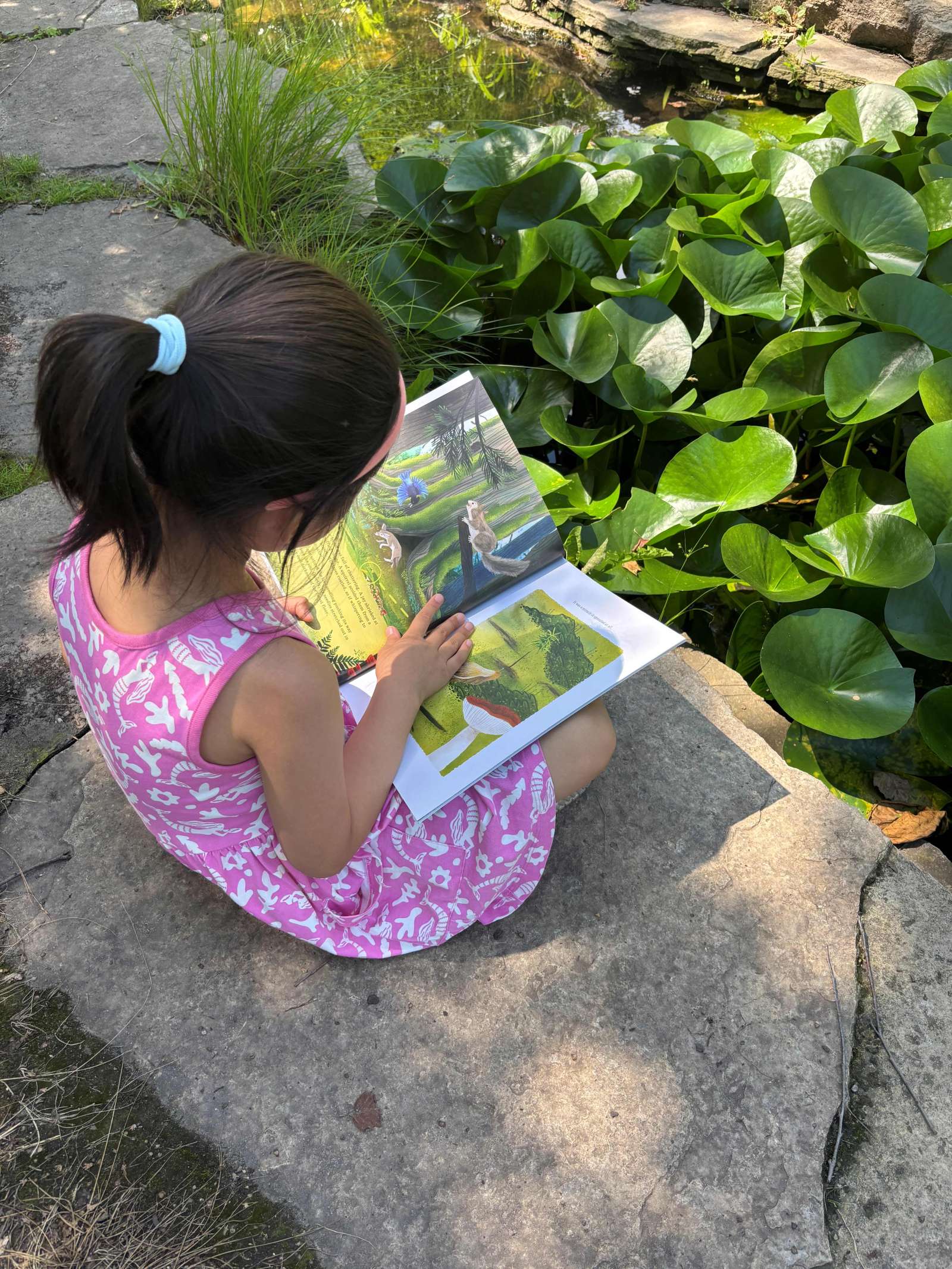 Young girl reading a book in a garden