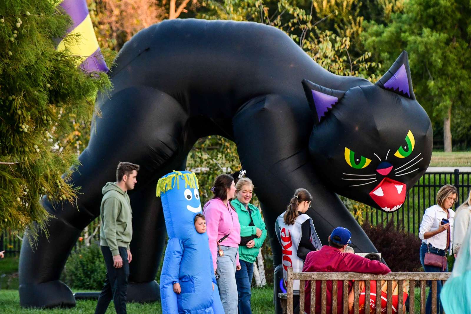 People in costume walking in front of a giant inflatable black cat